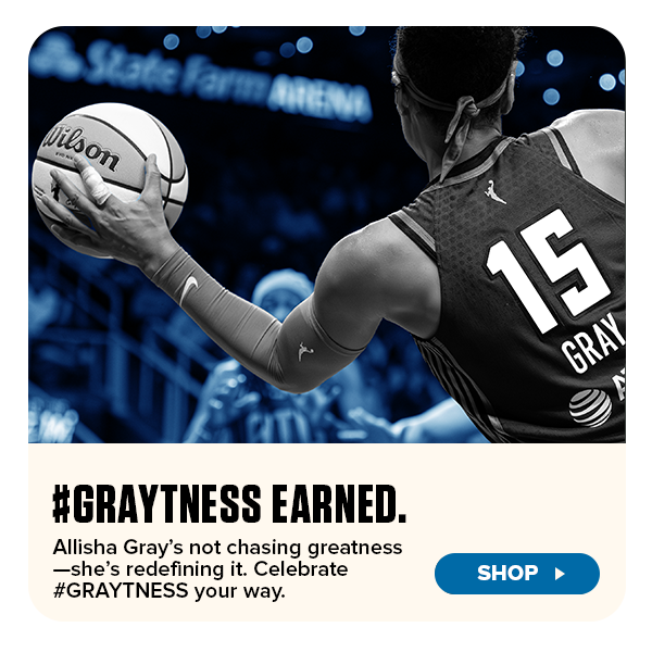 Promotional banner featuring WNBA player Allisha Gray in an action shot from behind, wearing jersey number 15 and holding a Wilson basketball. The text reads “#GRAYTNESS EARNED. Allisha Gray’s not chasing greatness—she’s redefining it. Celebrate #GRAYTNESS your way.” A blue “Shop” button appears below, inviting fans to purchase Atlanta Dream gear.